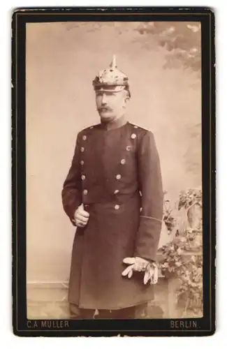 Fotografie C.A. Müller, Berlin, Chausseestr. 40, Soldat in Uniform mit Mantel & Pickelhaube