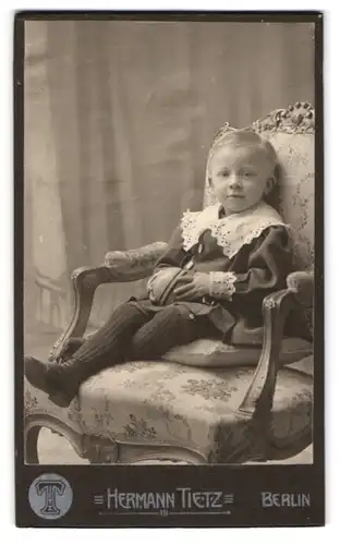 Fotografie Hermann Tietz, Berlin, Leipziger Strasse, Kleiner Junge in ordentlicher Kleidung mit Ball auf Stuhl