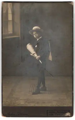 Fotografie Herm. Rudolph, Hof, Liebigstr., Portrait junger Knabe um Anzug mit Zuckertüte und Schulranzen, Schulanfang
