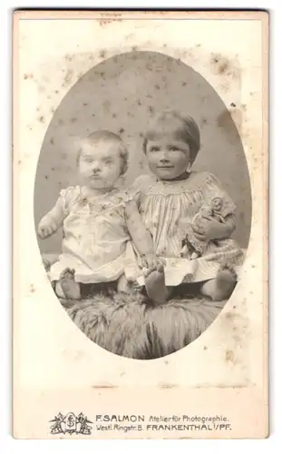 Fotografie F. Salmon, Frankenthal i /Pf., Westl. Ringst. 8, Portrait zwei süsse Kleinkinder in Kleidern mit Puppe