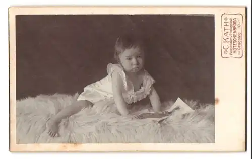Fotografie C. Kath, Kötzschenbroda, Gradsteg 10, Portrait süsses Kleinkind im weissen Hemd sitzt auf Fell