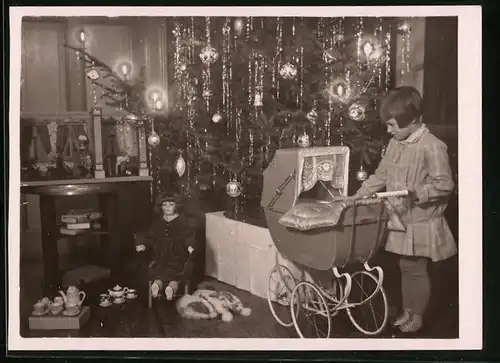 Fotografie Weihanachten 1929, Mädchen mit Puppenwagen, Puppe & Puppenstube neben Weihnachtsbaum