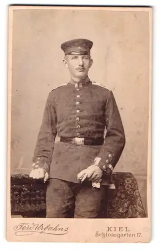 Fotografie Ferd Urbahns, Kiel, Schlossgarten 17, Portrait Soldat in Uniform mit Schirmmütze