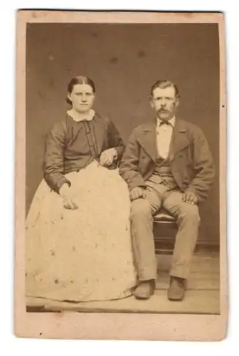 Fotografie unbekannter Fotograf und Ort, Portrait Frau und Mann im Anzug und Kleid posieren im Atelier, 1872