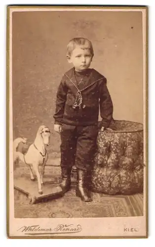 Fotografie Waldemar Renard, Kiel, Sophienblatt 18, Portrait junger Knabe im Anzug mit seinem Schaukelpferd