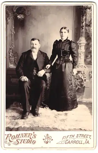 Fotografie Rohners Studio, Carroll / IA, Portrait amerikanisches Brautpaar im schwarzen Kleid und Anzug