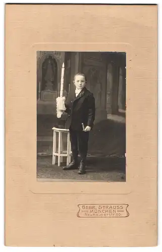 Fotografie Gebr. Strauss, München, Neuhauserstr. 20, Portrait junger Knabe im Anzug mit Kommunionskerze
