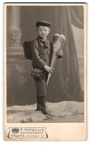 Fotografie E. Motzkus, Halle a. S., Ulrichstr. 57, Portrait junger Knabe mit Zuckertüte im Arm und Ranzen