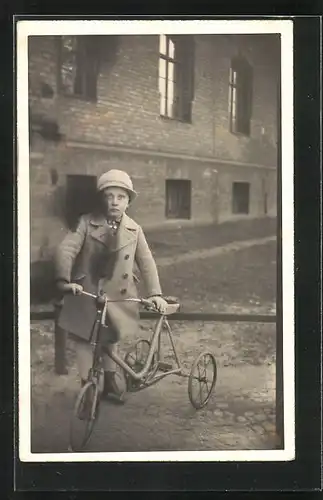 Foto-AK Kind schiebt mit Mütze und Mantel bekleidet sein Dreirad