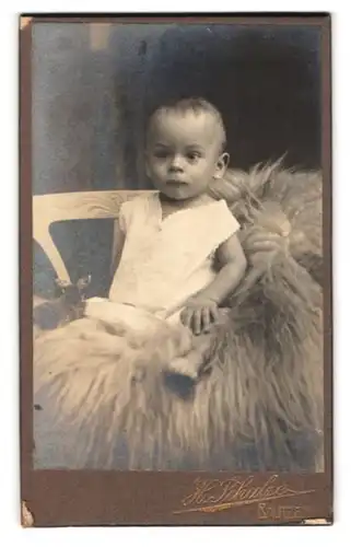 Fotografie H. Schulze, Bautzen, Visit-Portrait süsses Kleinkind im weissen Hemd sitzt auf Fell