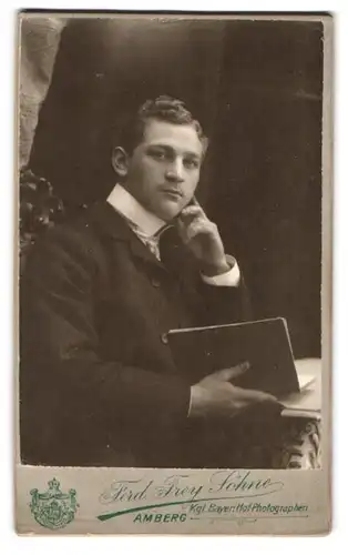 Fotografie Ferd. Frey Söhne, Amberg, Portrait junger Herr im Anzug mit Buch in der Hand