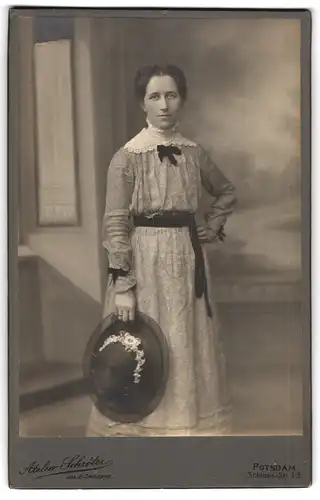 Fotografie Atelier Schröter, Potsdam, Schloss-Str. 1-3, Dame in gemustertem Kleid mit weissem Zierkragen hält einen Hut