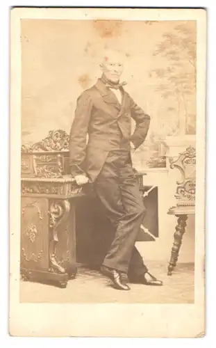 Fotografie Bruno Blücher, Altenberg, Markt 241, Portrait Pastor Knabe im Anzug lehnt an einem Sekretär