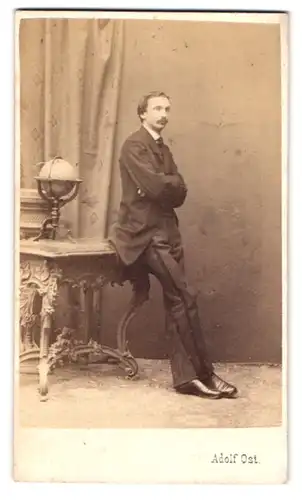 Fotografie Adolf Ost, Stadt, Strauchgasse 1, Portrait Mann im Anzug lehnt an Tisch mit Globus