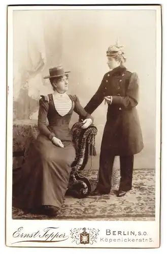 Fotografie Ernst Tepper, Berlin, Köpenickerstr. 5, Portrait Frau in Soldaten Uniform mit Pickelhaube nebst Freundin