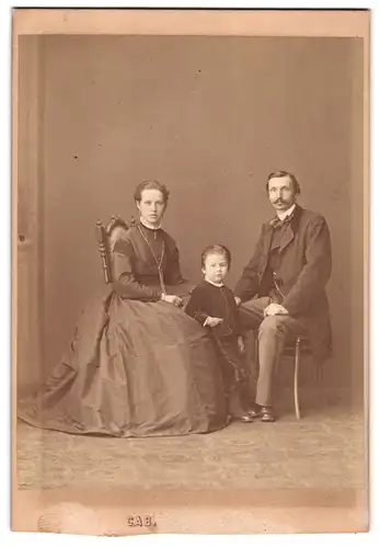 Fotografie unbekannter Fotograf und Ort, Portrait junge Eltern mit ihrem Sohn im Samtanzug, Mutterglück