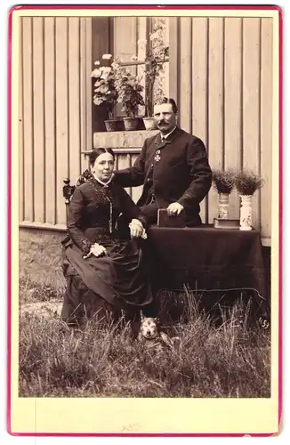 Fotografie unbekannter Fotograf und Ort, Portrait Mann im Anzug mit Eisernes Kreuz am Band, Frau und Hund im Garten