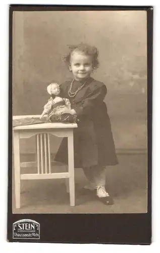 Fotografie F. Stein, Berlin, Chausseestr. 70 /71, Portrait kleines Mädchen mit Locken im Kleid samt Puppe, Perlenkette