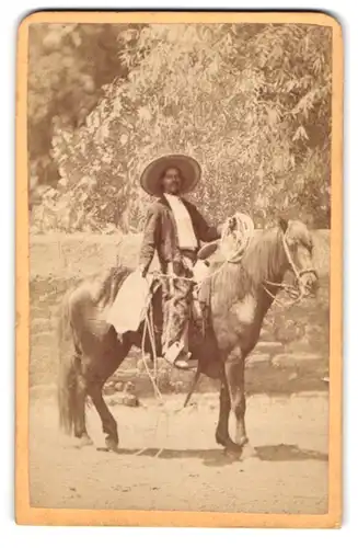 Fotografie unbekannter Fotograf und Ort, argentinischer Gaucho auf seinem Pferd mit Lasso