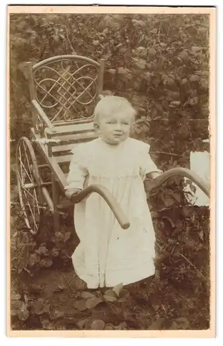 Fotografie unbekannter Fotograf und Ort, Portrait niedliches Mädchen im weissen Kleid mit Kinderwagen