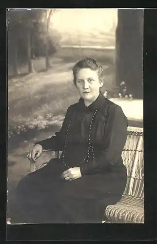 Foto-AK Ältere Frau auf einer Bank sitzend, Studiokulisse