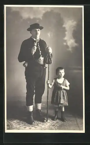 Foto-AK Mann in Tracht mit Pfeife und kleinem Mädchen, Studiokulisse