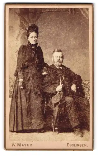 Fotografie Wilhelm Mayer, Esslingen, Portrait hübsch gekleidetes älteres Paar mit Schirm