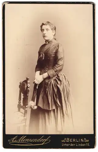 Fotografie A. Menzendorf, Berlin, Unter den Linden 15, junge Frau im feinen Kleid mit kleiner Tasche und Brosche