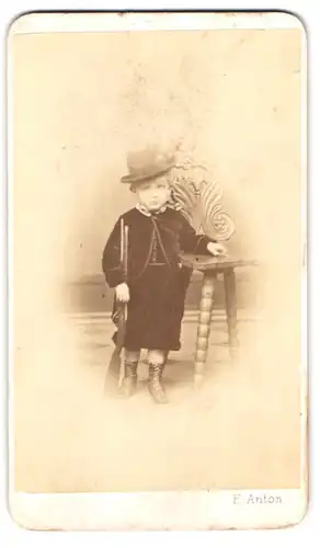 Fotografie E. Anton, Carlsbad, Portrait junger Knabe im Samtanzug mit Spielzeug Gewehr bei Fuss