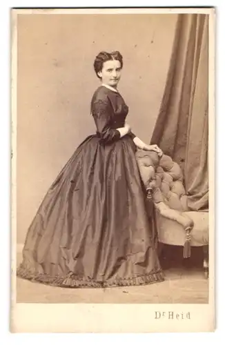 Fotografie Dr. Heid, Wien, Gärtnergasse 23, Portrait Frau Emilie im Biedermeierkleid stehend am Sessel