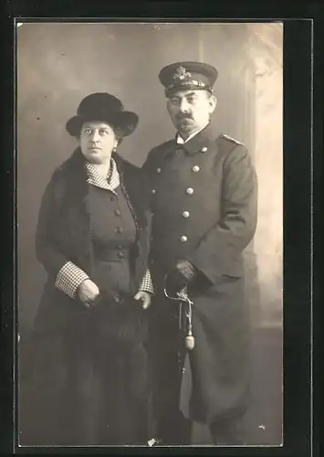 Foto-AK Oberbootsmann in Uniform mit Säbel und Frau, Uniformfoto