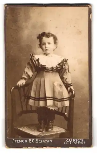 Fotografie F.C. Schmid, Zürich, Langstrasse, Mädchen im Sonntagskleid auf Stuhl stehend