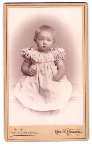 Fotografie J. Jensen, Quern Dingholz in Angeln, Baby mit verträumten Blick im Rüschenkleid