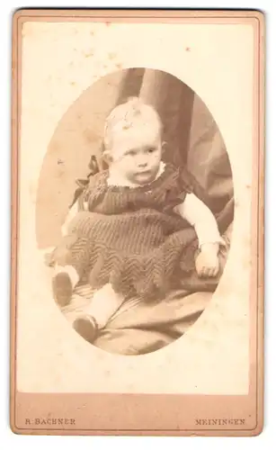Fotografie R. Bachner, Meiningen, Georgenstrasse 22, Kleinkind im Strickkleid, sitzend