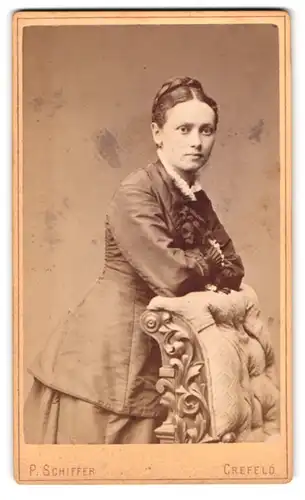 Fotografie P. Schiffer, Crefeld, Neue Linnerstrasse 74, junge hübsche Frau mit Flechtfrisur, auf Sessel lehnend