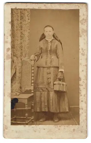 Fotografie unbekannter Fotograf und Ort, Portrait Frau trägt Trachtenkleid und Köfferchen in der Hand