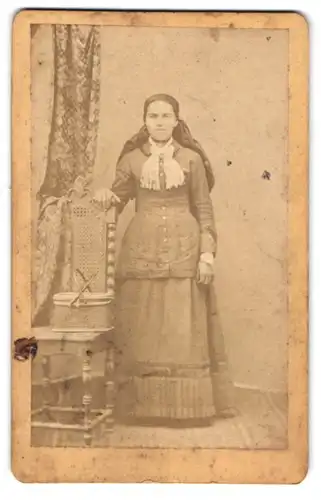 Fotografie unbekannter Fotograf und Ort, Portrait junge Frau im Trachtenkleid mit Picknick Korb auf dem Stuhl