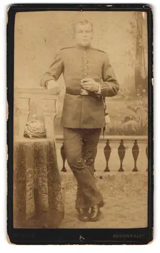 Fotografie M. Wild, Burghausen, Portrait Soldat in Uniform nebst Pickelhaube, rauchend im Atelier