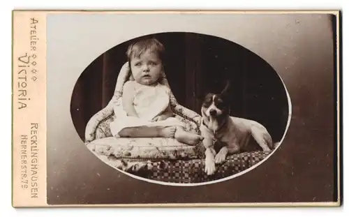 Fotografie Victoria, Recklinghausen, Hernerstr. 7, Portrait kleines Kind im Kleidchen mit Hund auf einem Sessel