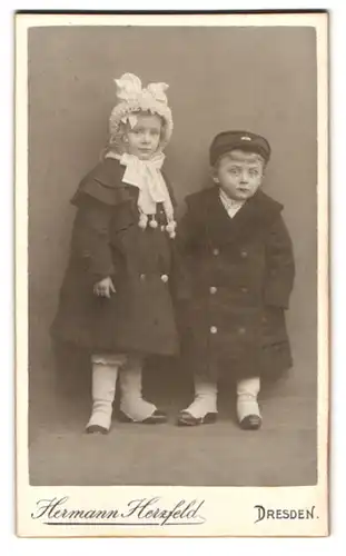 Fotografie Hermann Herzfeld, Dresden, Altmarkt, Portrait niedlicher Kinderpaar mit Mützen in Mänteln
