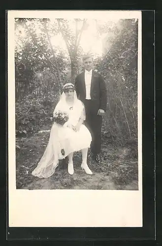 AK Schönes junges Brautpaar mit Hochzeitsmode im Garten