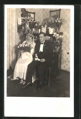 AK Junges Brautpaar sitzt in eleganter Hochzeitsmode in der Stube