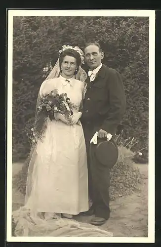 AK Portrait eines Brautpaares in eleganter Hochzeitsmode im Garten stehend