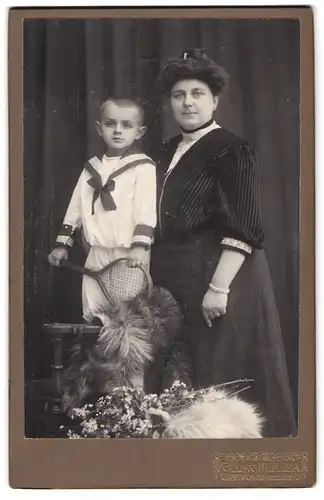 Fotografie Georg Müller, Cöpenick, Schlossstrasse 16, Sohn im Matrosenanzug mit Tennisschläger steht neben seiner Mutter