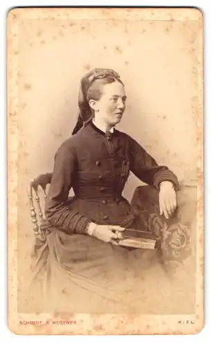 Fotografie Schmidt & Wegener, Kiel, Dänische Strasse 35, Junge adrett-gekleidete Frau auf Stuhl mit Buch