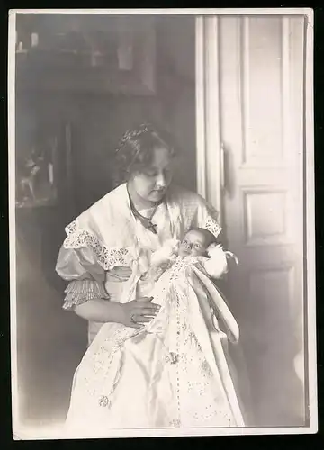 Fotografie Mutterglück, junge Mutter hält Baby im Taufkleid