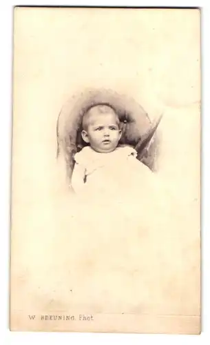 Fotografie W. Breuning, Hamburg, Steindamm 144, Kleinkind in weisser Kleidung auf Stuhl liegend