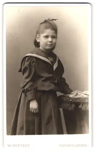 Fotografie W. Höffert, Hamburg, Esplanade 47, Junges Mädchen in schönem Kleid an Tisch gelehnt