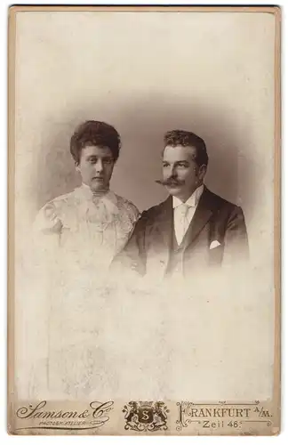 Fotografie Samson & Co, Frankfurt a. M., Zeil 36, Mann und Frau mit lockigem Haar in feiner Kleidung