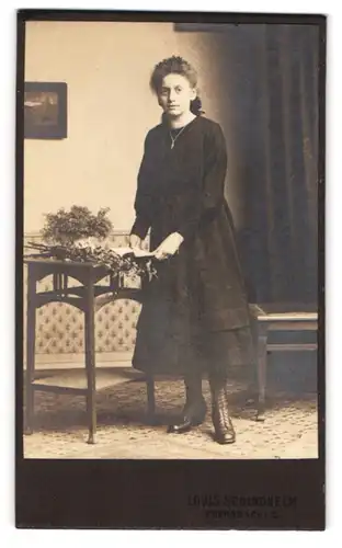 Fotografie Louis Schindhelm, Ebersbach, Junge Dame in schwarzem Kleid und Lederstiefeln